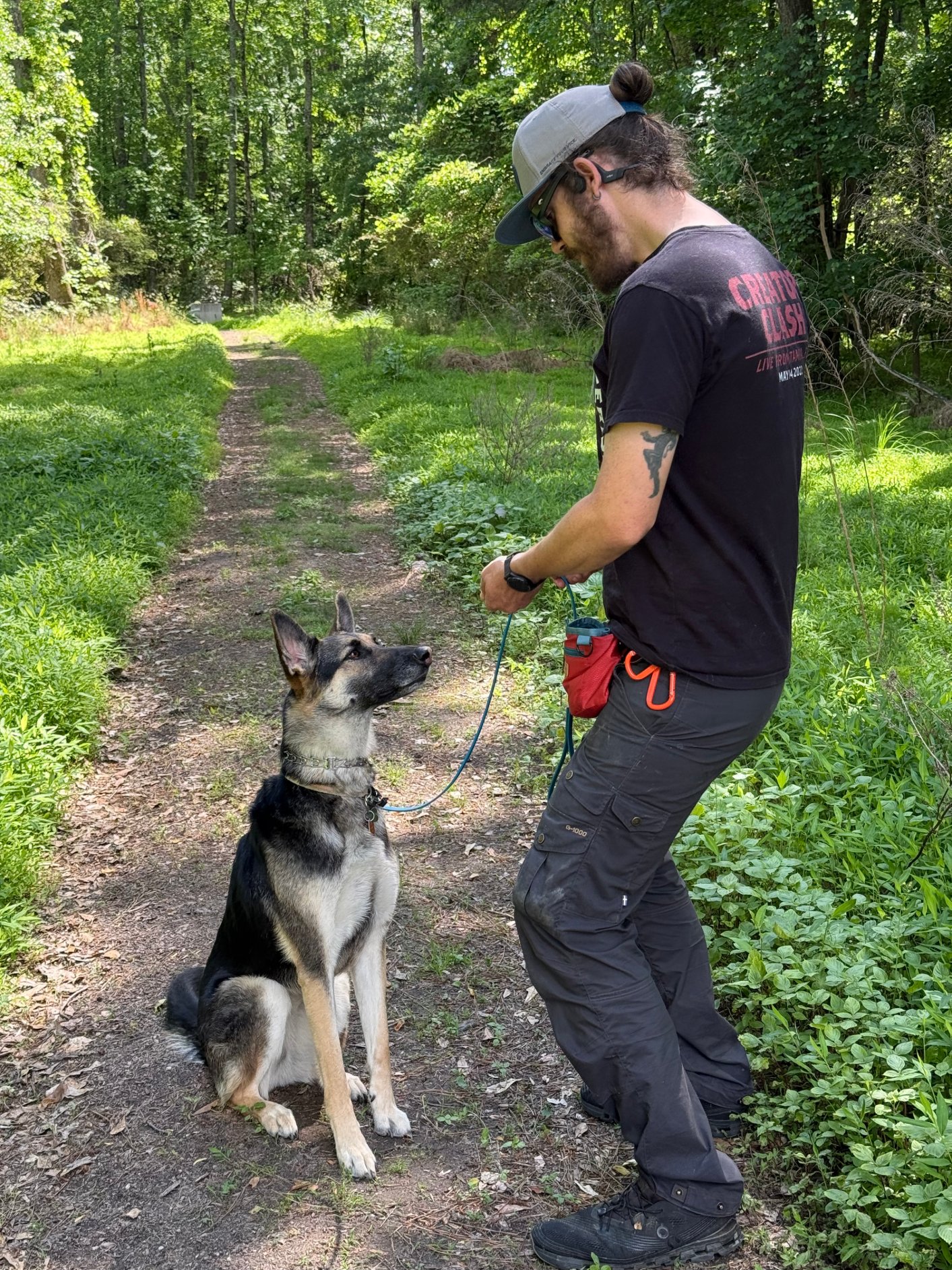 Brett training an attentive German Shepherd on a wooded trail
